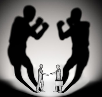 Two businessman casting a shadow shaped like two fighters